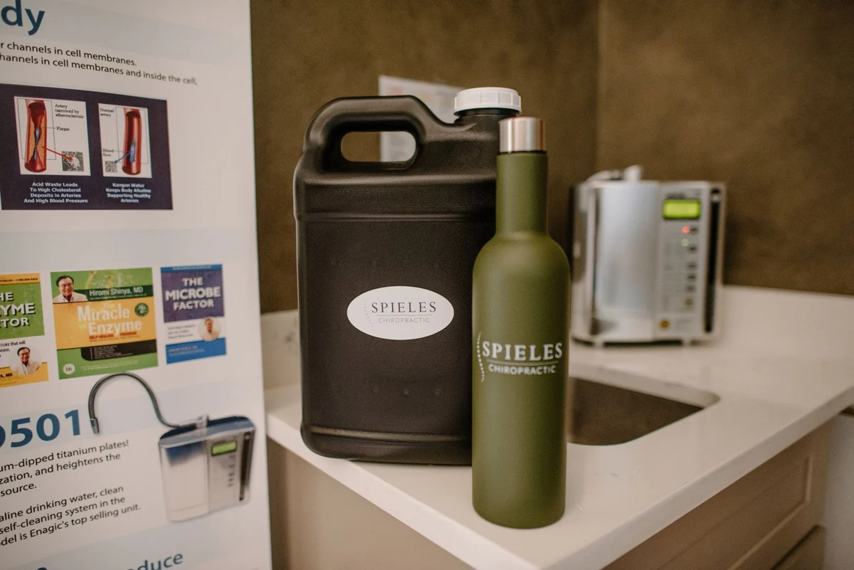 Spieles Chiropractic branded water jug and bottle beside the clinic’s Kangen Water system